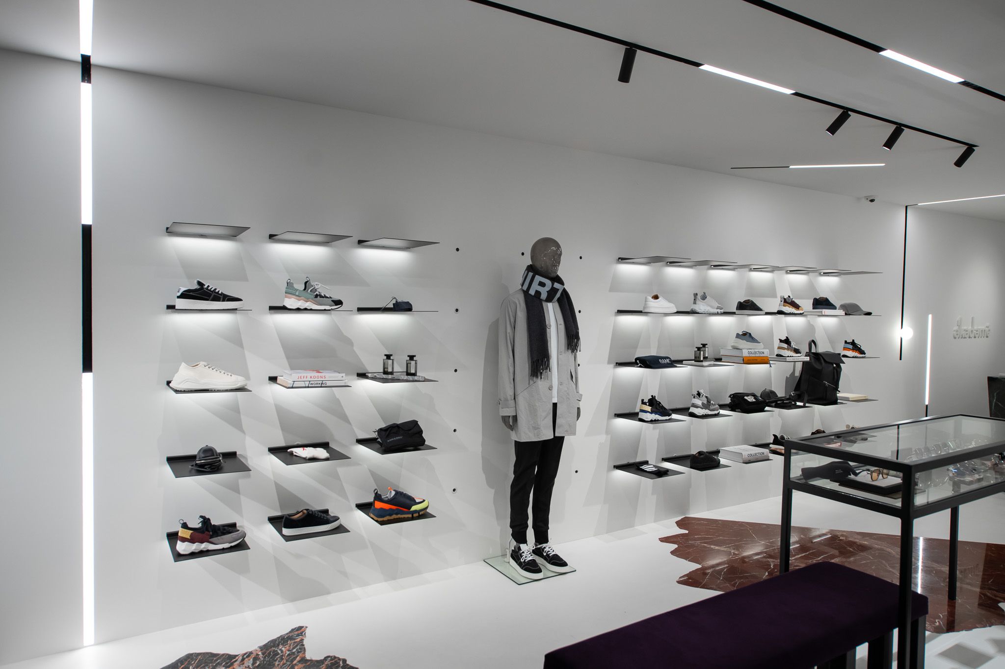 Detail view of the retail space in the Ekademe store in Utrecht, with stylish garments on minimalist and electrified metal shelves by Visplay.