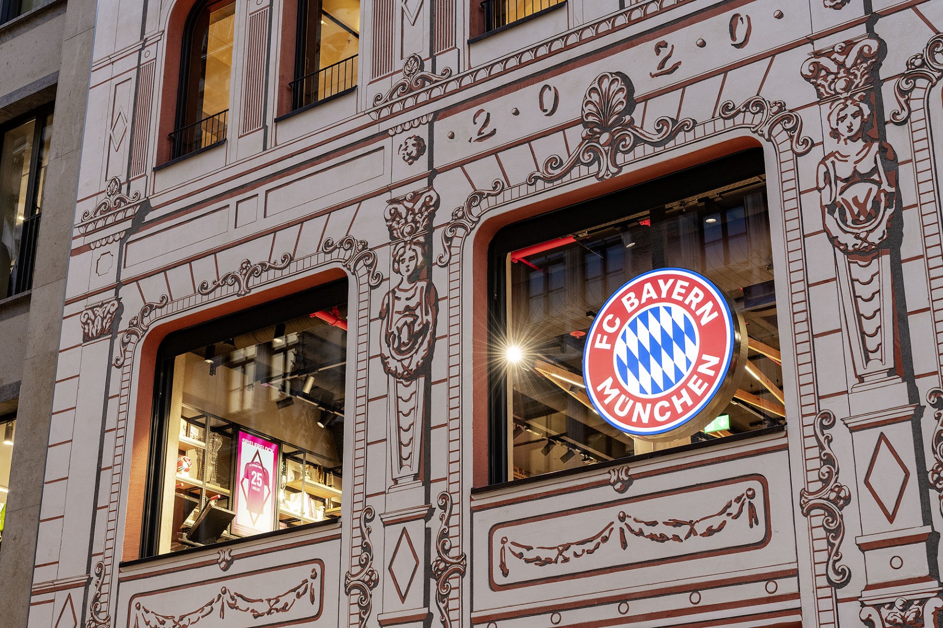 Facade of a building with FC Bayern Munich logo in the window.