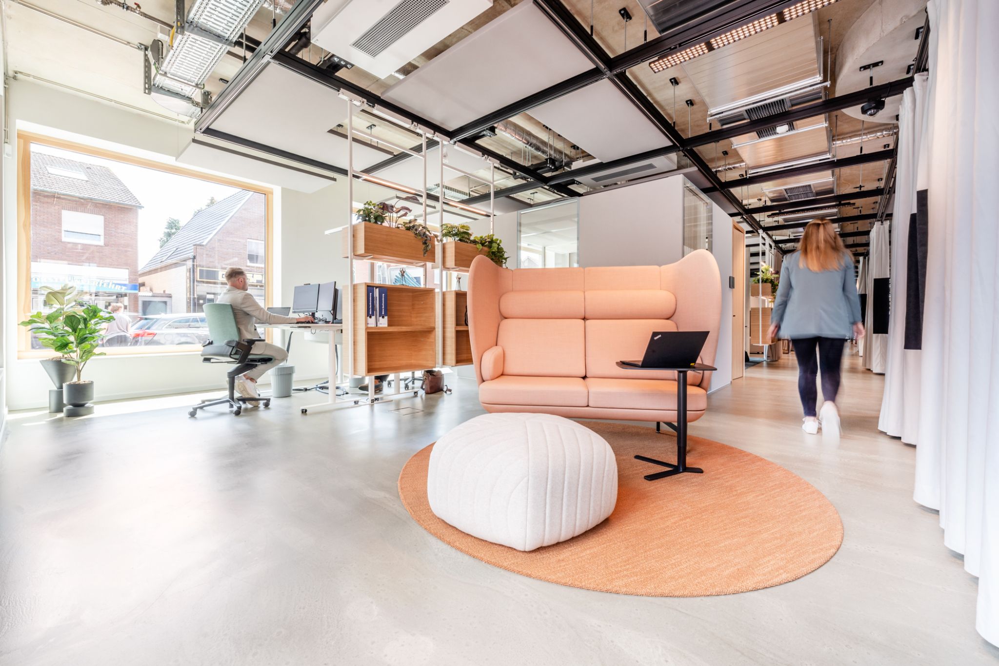 Modern, minimalist interior design of the office spaces in a bank branch with elegant lighting, bright walls, and a floating ceiling structure, furnished by Visplay for Grafschafter Volksbank.