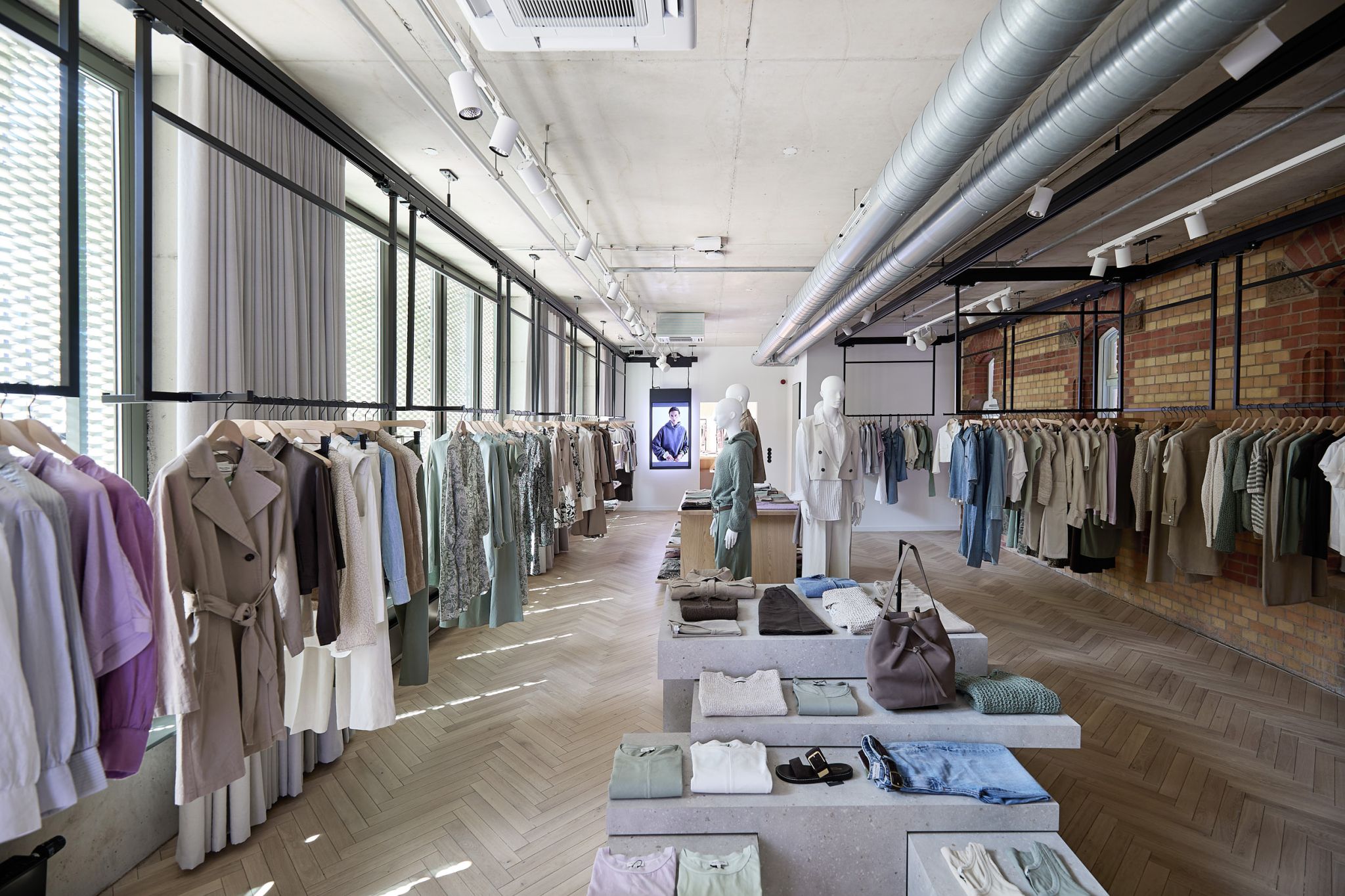 Marc O'Polo showroom featuring ceiling-mounted garment rails as a flexible display solution for hanging merchandise.