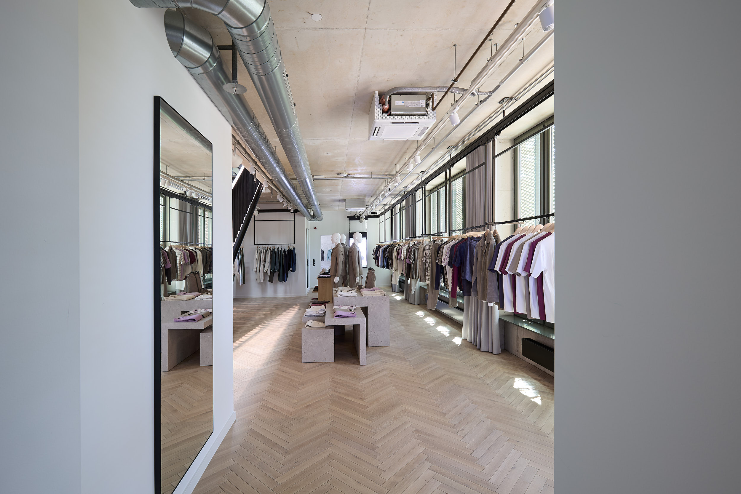 A showroom with modular wall systems where clothing and accessories are displayed on clearly structured shelves and metal supports.