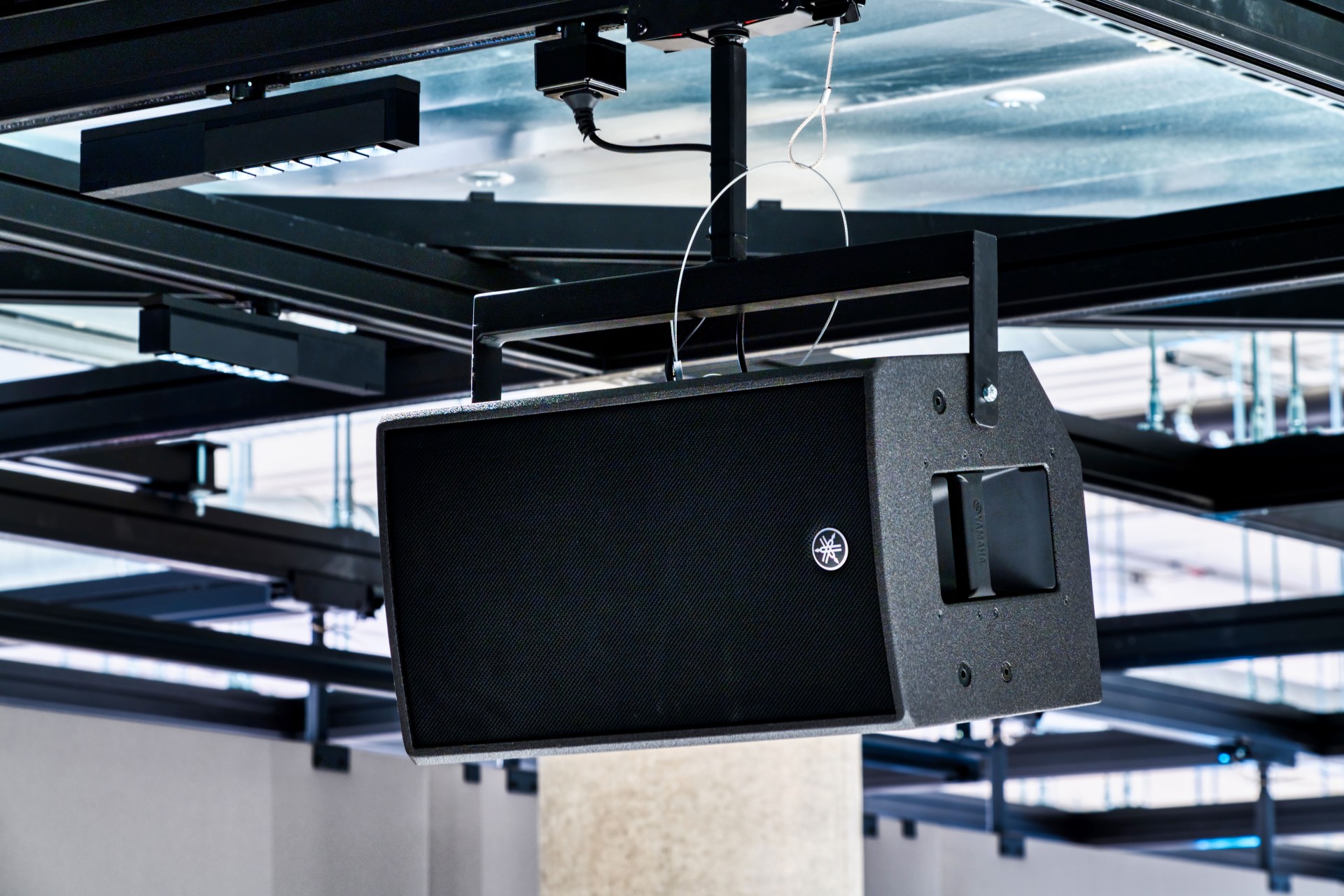 Close-up of a speaker integrated into a ceiling rail system.