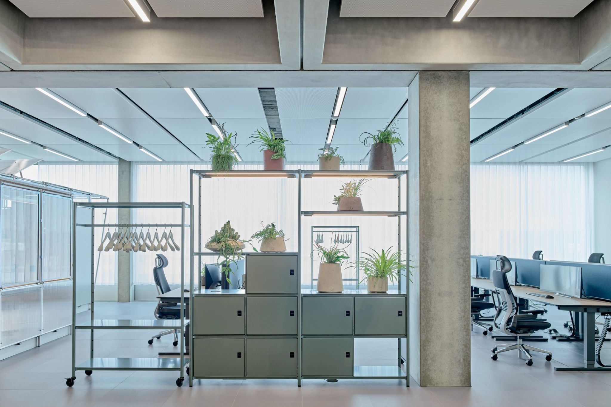 A ready-to-wear rack with a blue shelving system in the foreground of a large office.