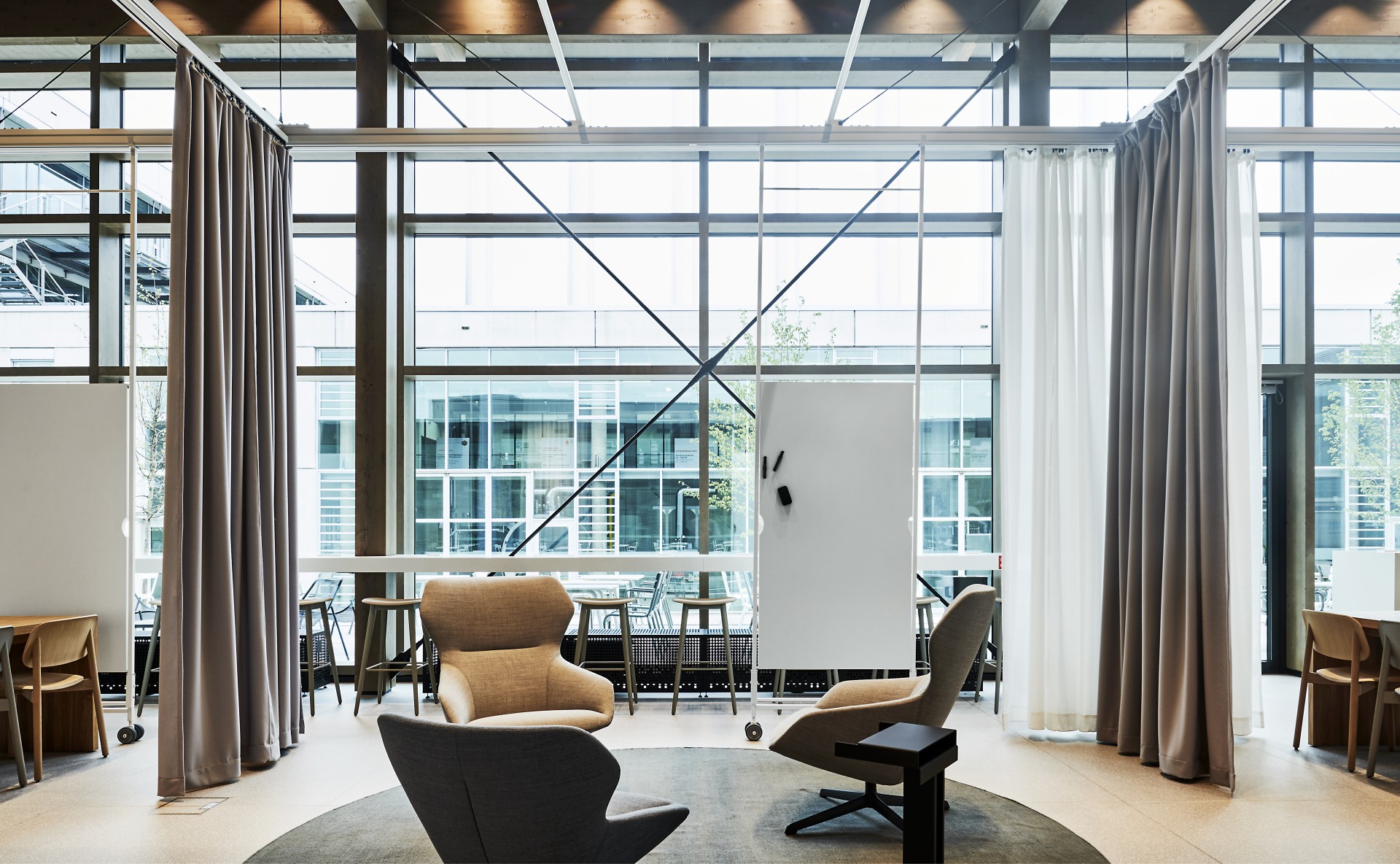 Room with a seating area and whiteboards hanging from the ceiling.